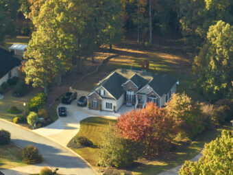 Aerial view of new family house between yellow trees in South Carolina suburban area in fall season. Real estate development in american suburbs