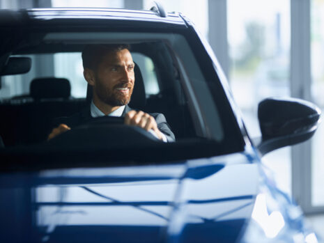 Businessman in suit buying new car at modern salon