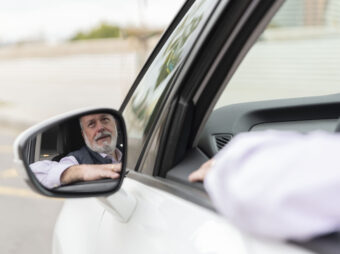 Reflection of an elder driver in the side mirror