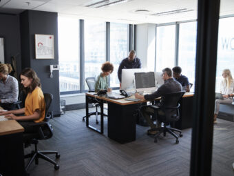 Young creative team working together at computers in a casual office, seen from doorway